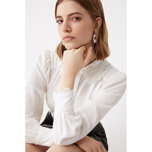 The Suncoo Lassie Blouse is a stylish, versatile choice for any wardrobe. It features a classic white shirt with an embroidered collar and sleeve cuff, perfect for layering under knit vests or jumpers or adding a pop of texture to a suit outfit. Crafted with subtle sophistication, this blouse will become a wardrobe favourite.