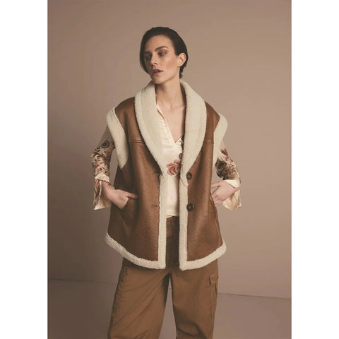 This lammy gilet is sleeveless and has an oversized fit. The gilet’s cuffs are made of teddy fabric. The lapel-style neckline has extra-wide faming with teddy, accentuating the neckline. The lammy jacket has two large buttons and slit pockets in the front.